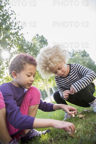 Mixed race sisters examining mushrooms outdoors