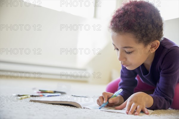 Mixed race girl coloring on floor