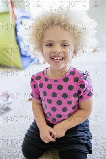 Mixed race girl smiling on bedroom floor