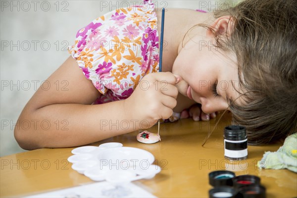 Caucasian girl painting rock on desk