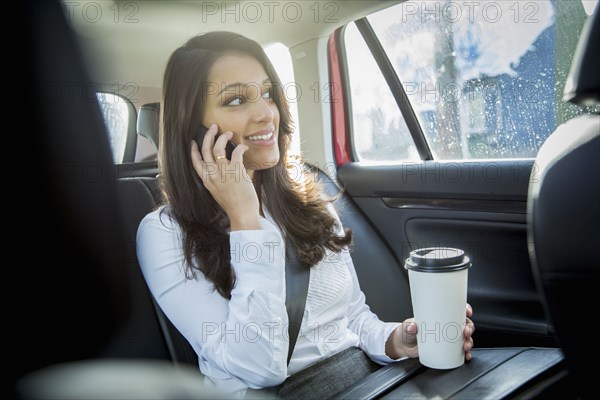 Mixed race businesswoman talking on cell phone in taxi