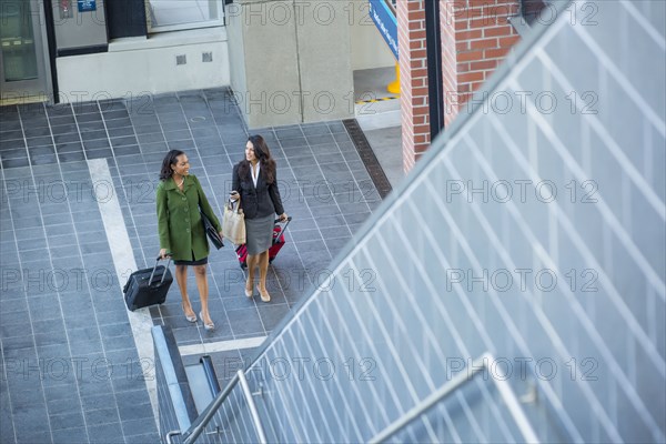 Businesswomen with suitcases near escalator