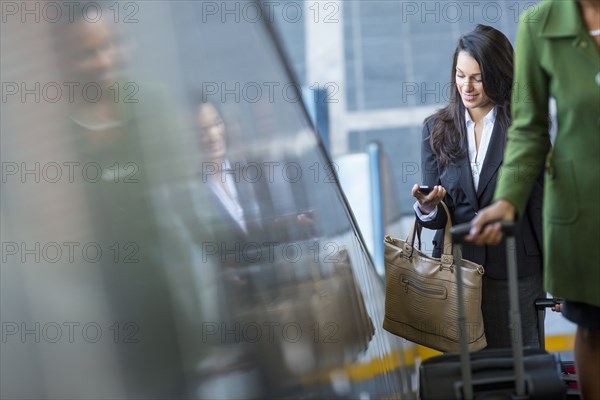 Mixed race businesswoman using cell phone on escalator