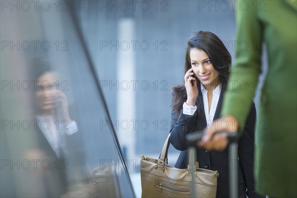 Mixed race businesswoman talking on cell phone on escalator