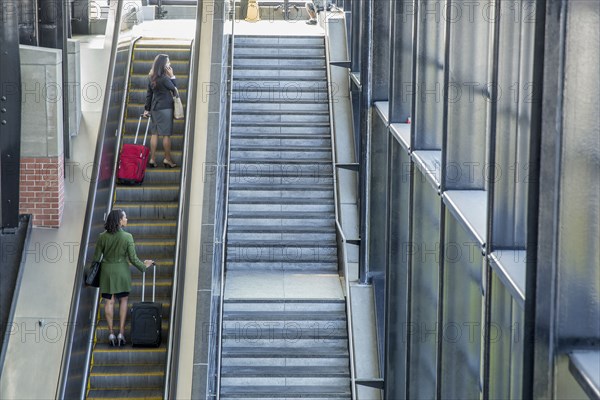 Businesswomen riding escalator