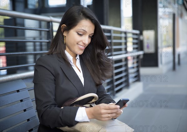 Mixed race businesswoman using cell phone on train platform