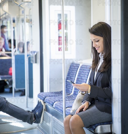 Mixed race businesswoman using cell phone on train