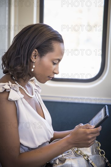 Black businesswoman using digital tablet on train