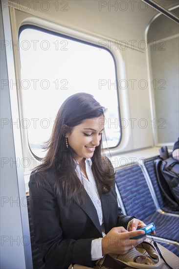 Mixed race businesswoman using cell phone on train