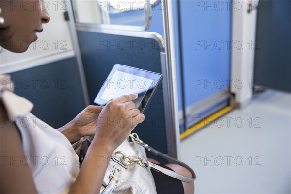 Black businesswoman using digital tablet on train