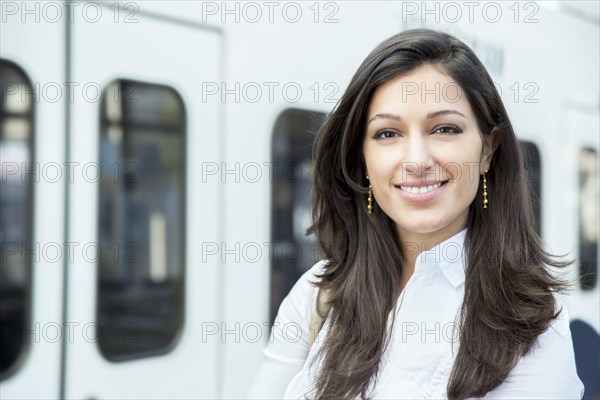 Mixed race businesswoman smiling on train platform