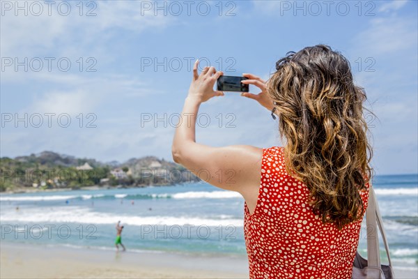 Mixed race woman taking pictures of tropical beach