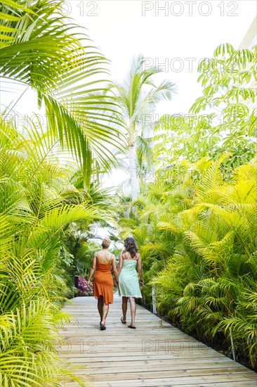 Lesbian couple holding hands on tropical walkway