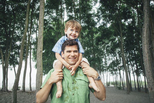 Man carrying son on wooded beach