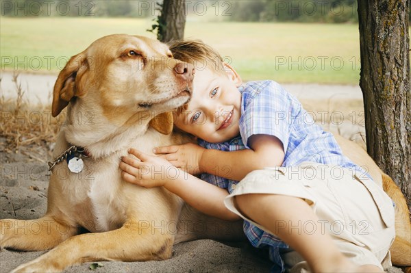 Boy hugging dog on wooded beach