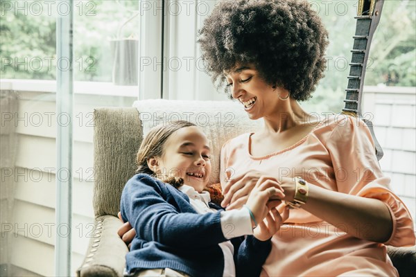 Mixed race mother holding daughter in armchair