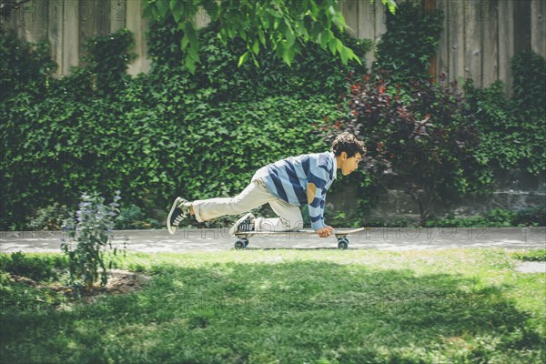 Mixed race boy riding skateboard on sidewalk