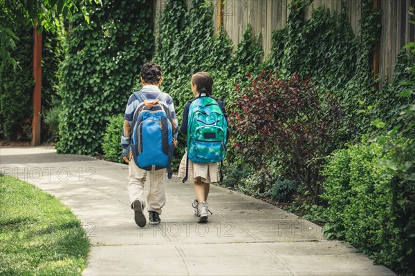 Mixed race brother and sister walking on sidewalk