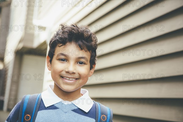 Mixed race boy smiling near house