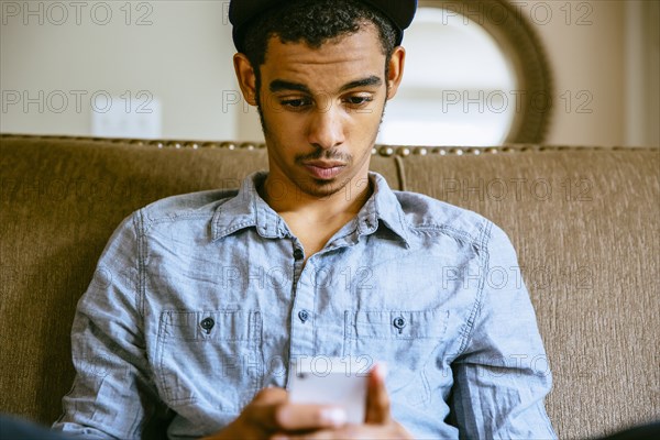 Mixed race boy using cell phone on sofa