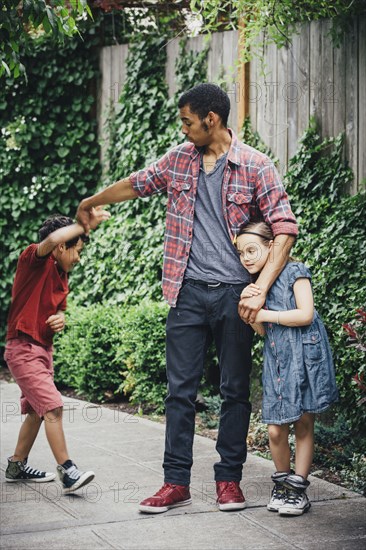 Mixed race brothers and sister playing on suburban sidewalk