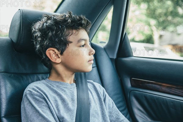 Mixed race boy sitting in car back seat