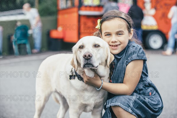 Mixed race girl hugging dog on street