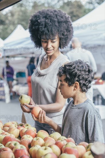Mixed race boy shopping with mother at farmers market