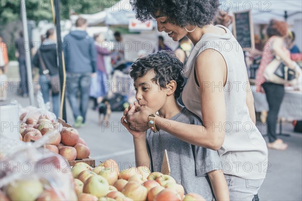 Mixed race boy shopping with mother at farmers market