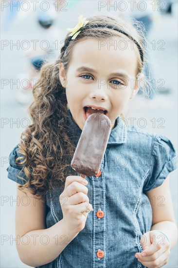 Mixed race girl eating fudgesicle on city street