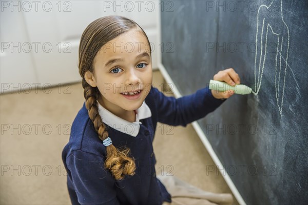 Mixed race girl drawing on chalkboard