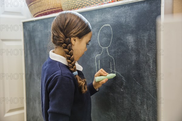 Mixed race girl drawing on chalkboard