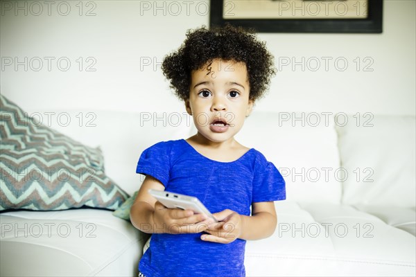 Mixed race girl using cell phone in living room