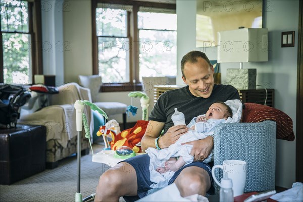 Caucasian father feeding baby boy in living room