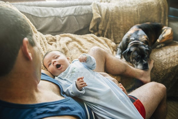 Caucasian father holding yawning baby boy in living room