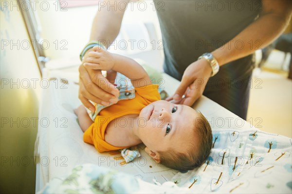 Caucasian father changing diaper of baby boy