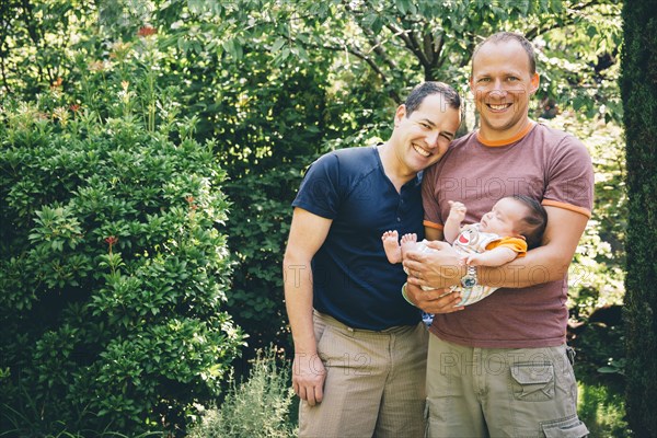 Caucasian gay couple holding baby boy outdoors