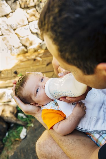 Caucasian father feeding baby boy outdoors