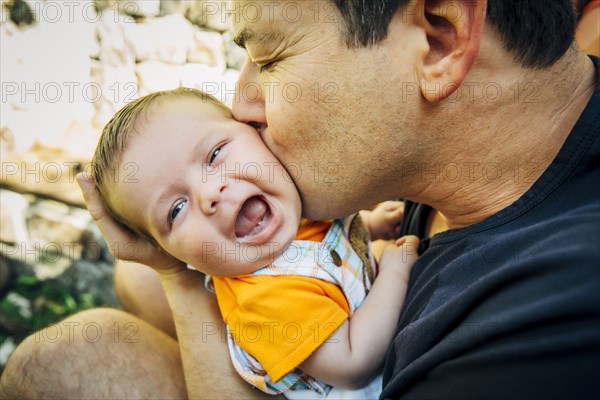 Caucasian father kissing baby boy outdoors