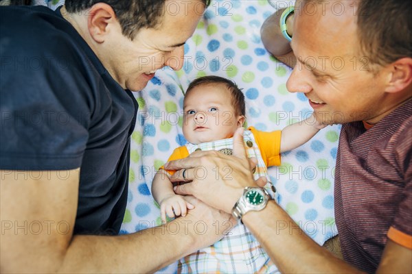 Caucasian gay couple cuddling baby boy