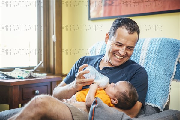 Caucasian father feeding baby boy in living room