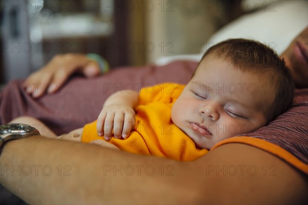 Caucasian father and baby boy sleeping on bed