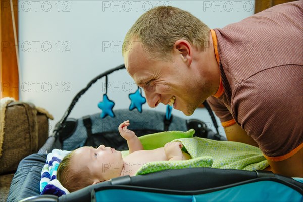 Caucasian father admiring baby boy on crib