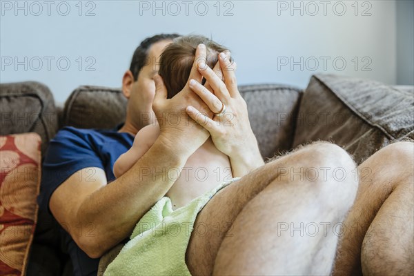 Caucasian father holding baby boy on sofa