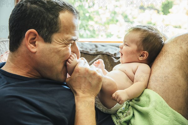 Caucasian father kissing feet of baby boy