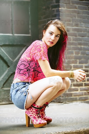 Caucasian woman crouching on sidewalk