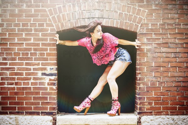 Caucasian woman crouching in alcove on sidewalk