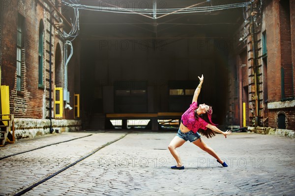 Caucasian woman dancing on cobblestone street