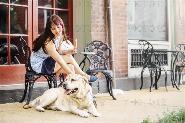 Caucasian woman petting dog at sidewalk cafe