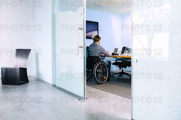 Businessman in wheelchair working at desk in office